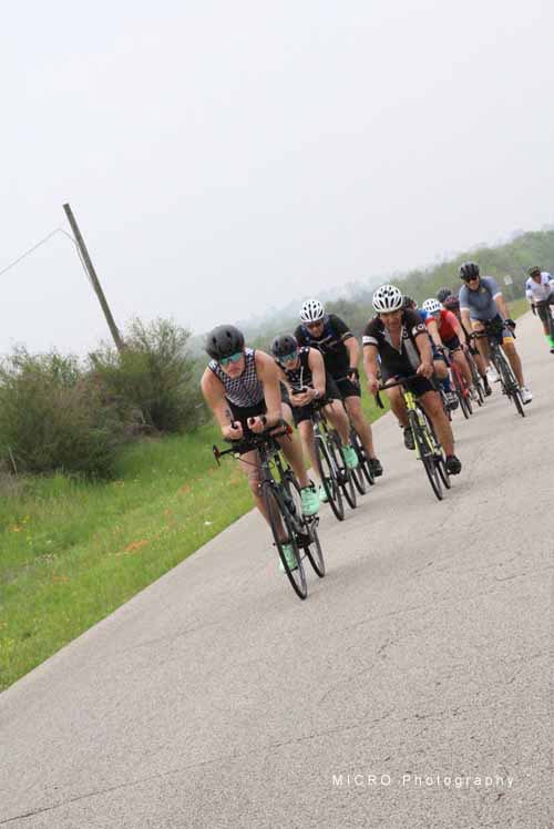 Cyclists riding together on scenic rural road during Bluebonnet Express event.