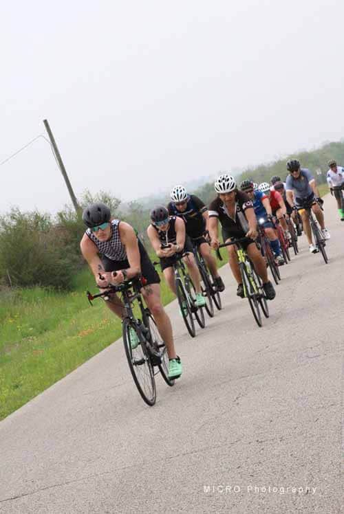 Group of cyclists riding on a countryside road during daytime.