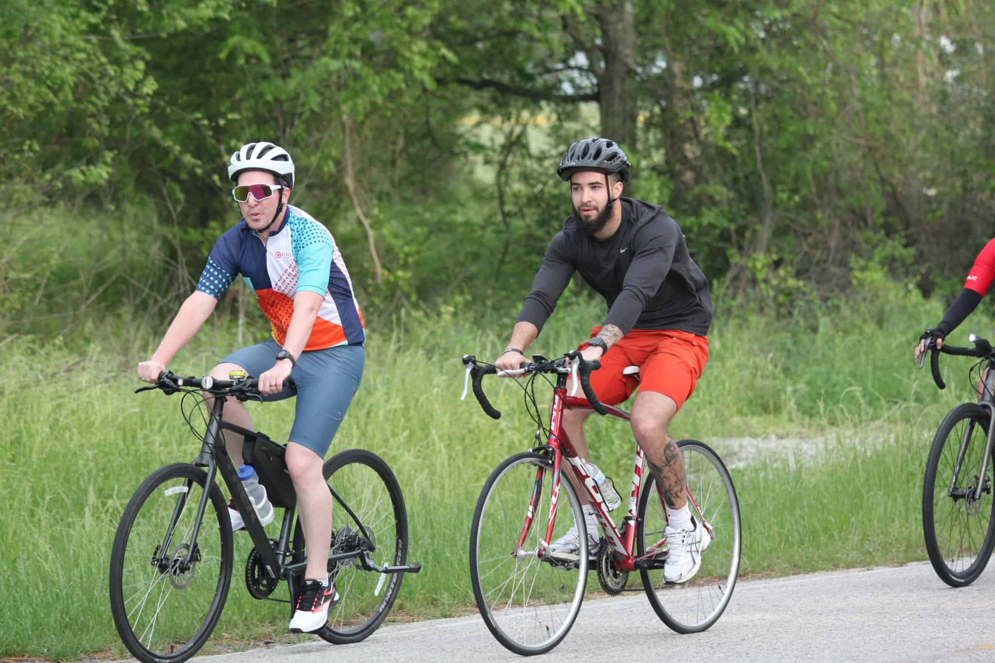 Brightly dressed cyclists enjoying a ride on the Bluebonnet Express bike trail in lush green surroundings.