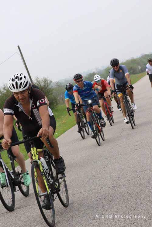 Vibrant group of cyclists riding on scenic open road during Bluebonnet Express event, promoting outdoor cycling activities.