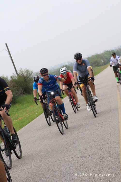Brightly colored cyclists riding together on a scenic rural road during daytime.