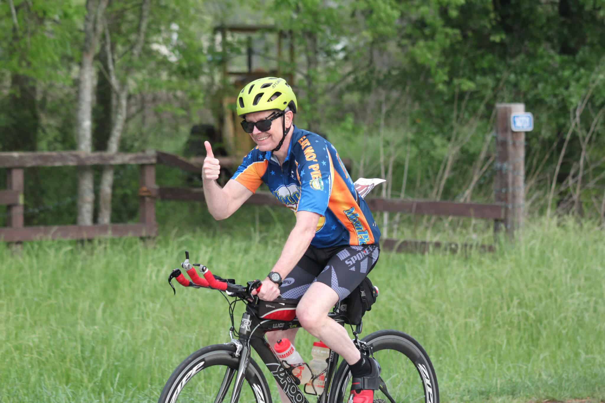 Vibrant cyclist smiling and giving thumbs-up on Bluebonnet Express bike trail.