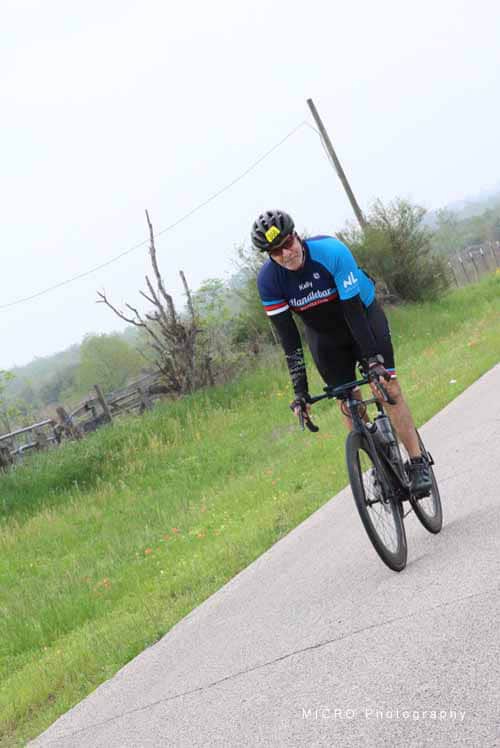 Vintage cyclist riding on scenic rural road near Bluebonnet fields during spring.