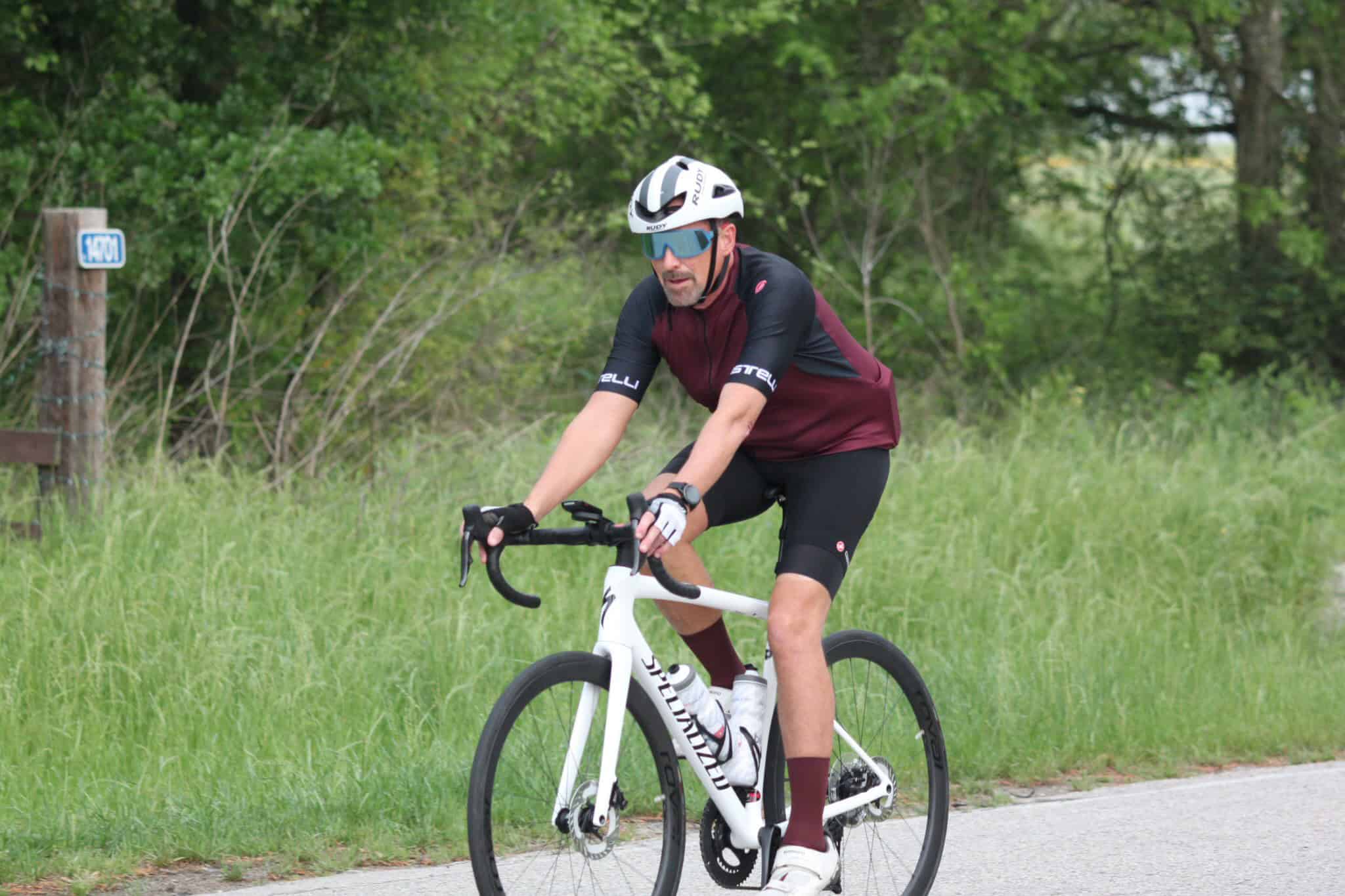 Bike rider on Specialized road bike on trail in green outdoor scenery.