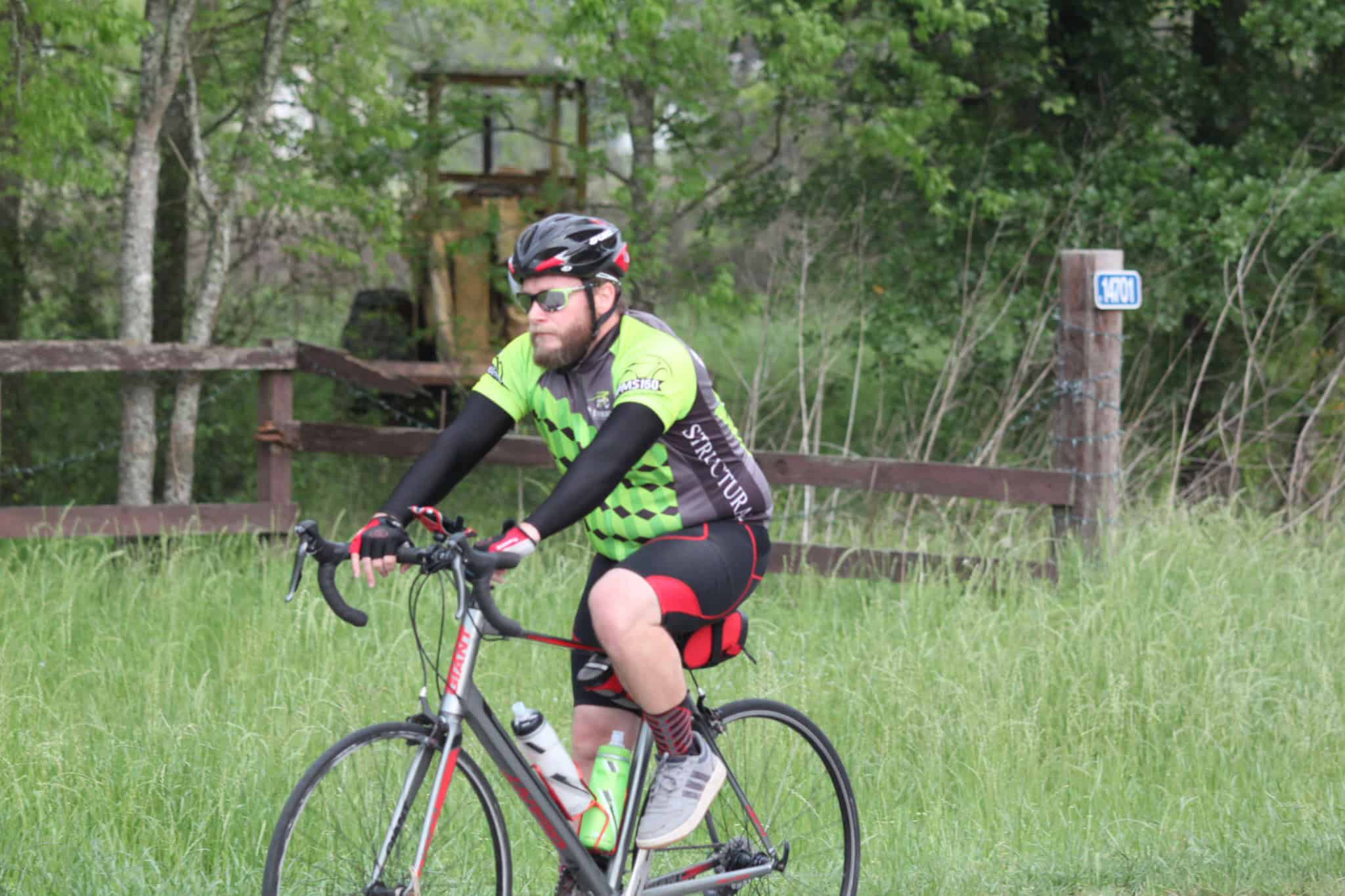 Vibrant cyclist riding on scenic trail amid greenery, promoting outdoor biking adventures by Bluebonnet Express.