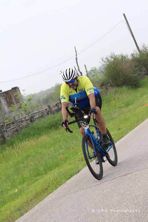 High-performance cyclist riding blue bike on scenic rural road.