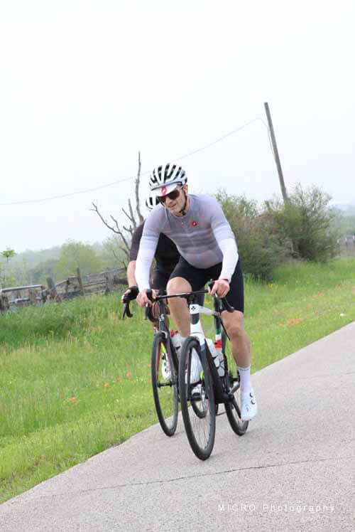 Bright cyclist riding a mountain bike on a rural path during daytime.
