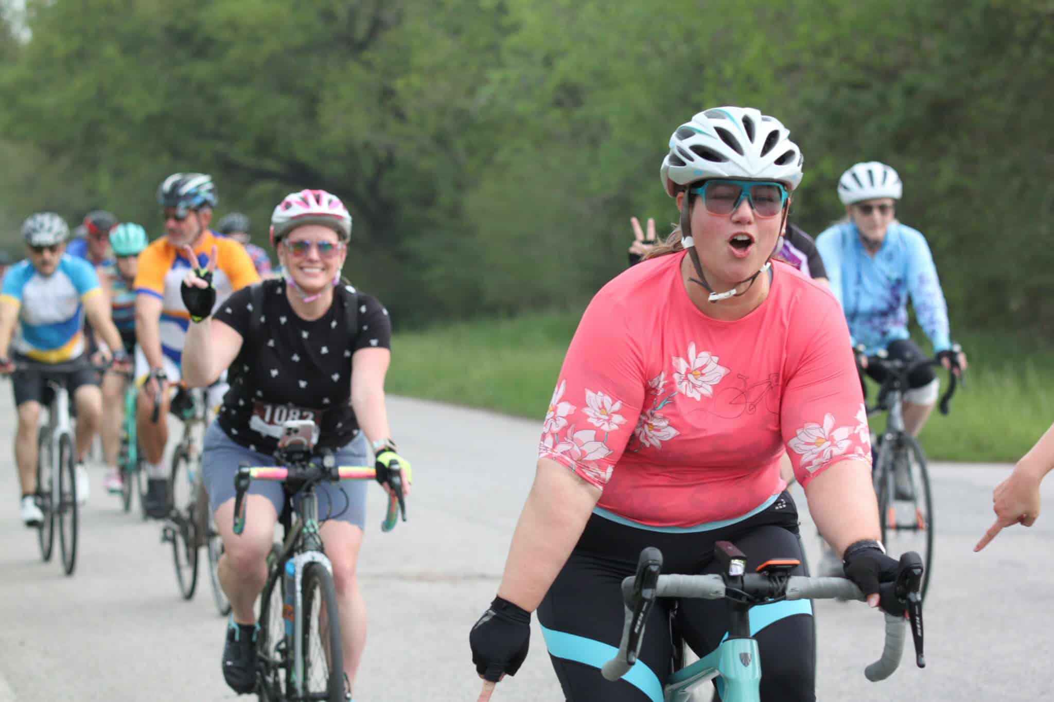 Bright smiling woman riding a bike on the Bluebonnet Express outdoor trail.