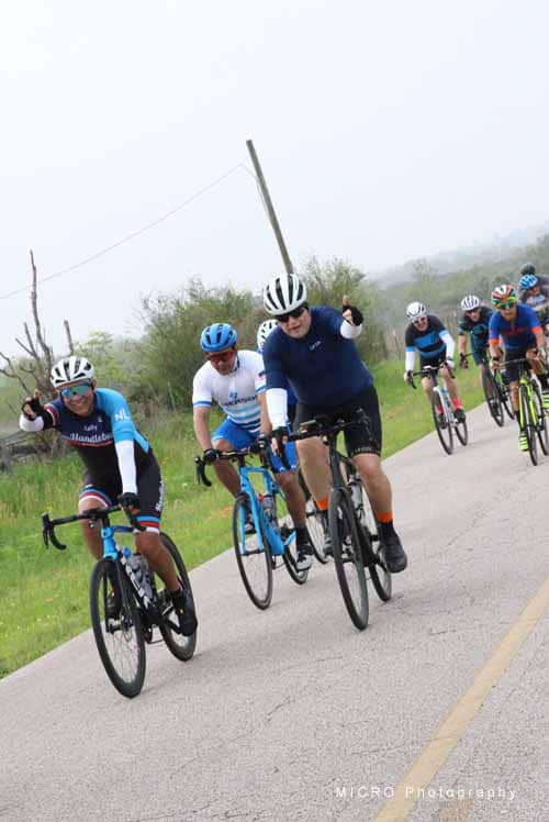 Cyclists riding together during Bluebonnet Express cycling event on scenic rural road in Texas.