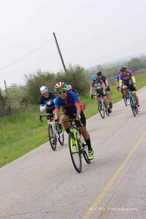 Cyclists riding on a foggy rural road during Bluebonnet Express bike race.