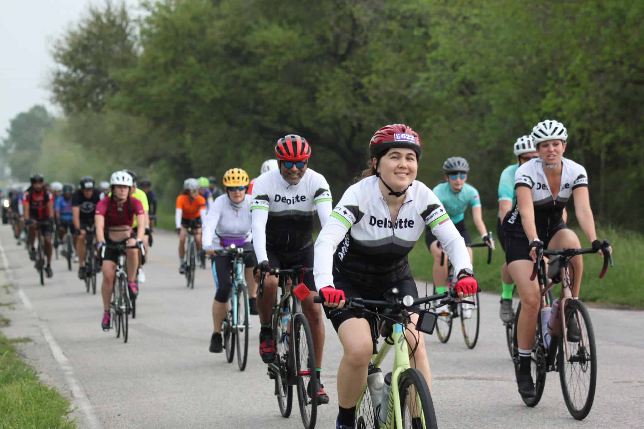 Vibrant group of cyclists participating in Bluebonnet Express charity bike ride amidst green scenic landscape.
