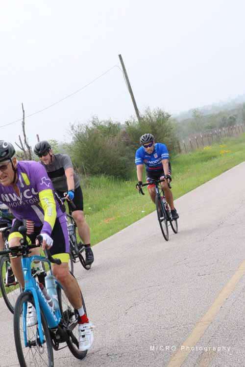 Cyclists riding lorsem cycling event on rural road during daytime.