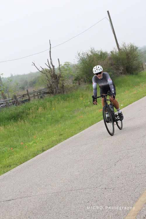 Bright cyclist on a scenic rural bike trail with lush greenery and overcast skies.
