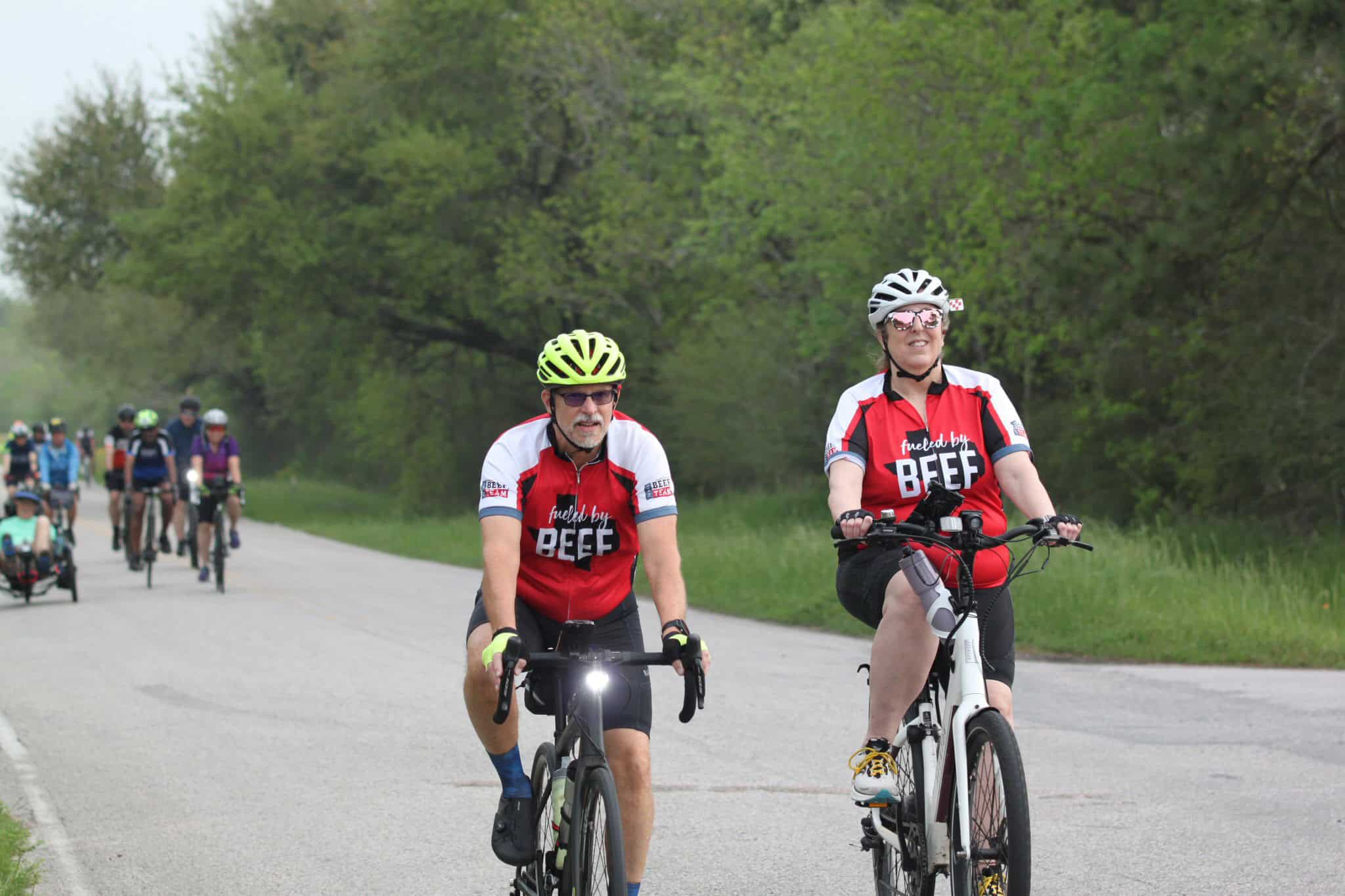 Brightly dressed cyclists riding on a scenic trail during a group biking event.