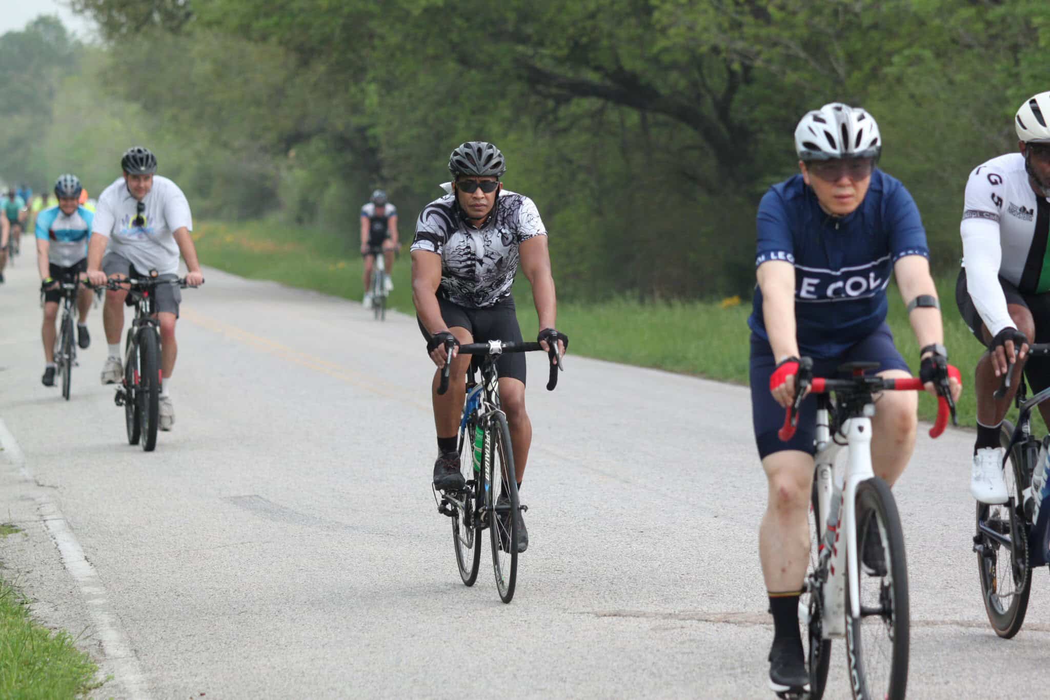 Cyclists riding on scenic Texas countryside road during Bluebonnet Express event.