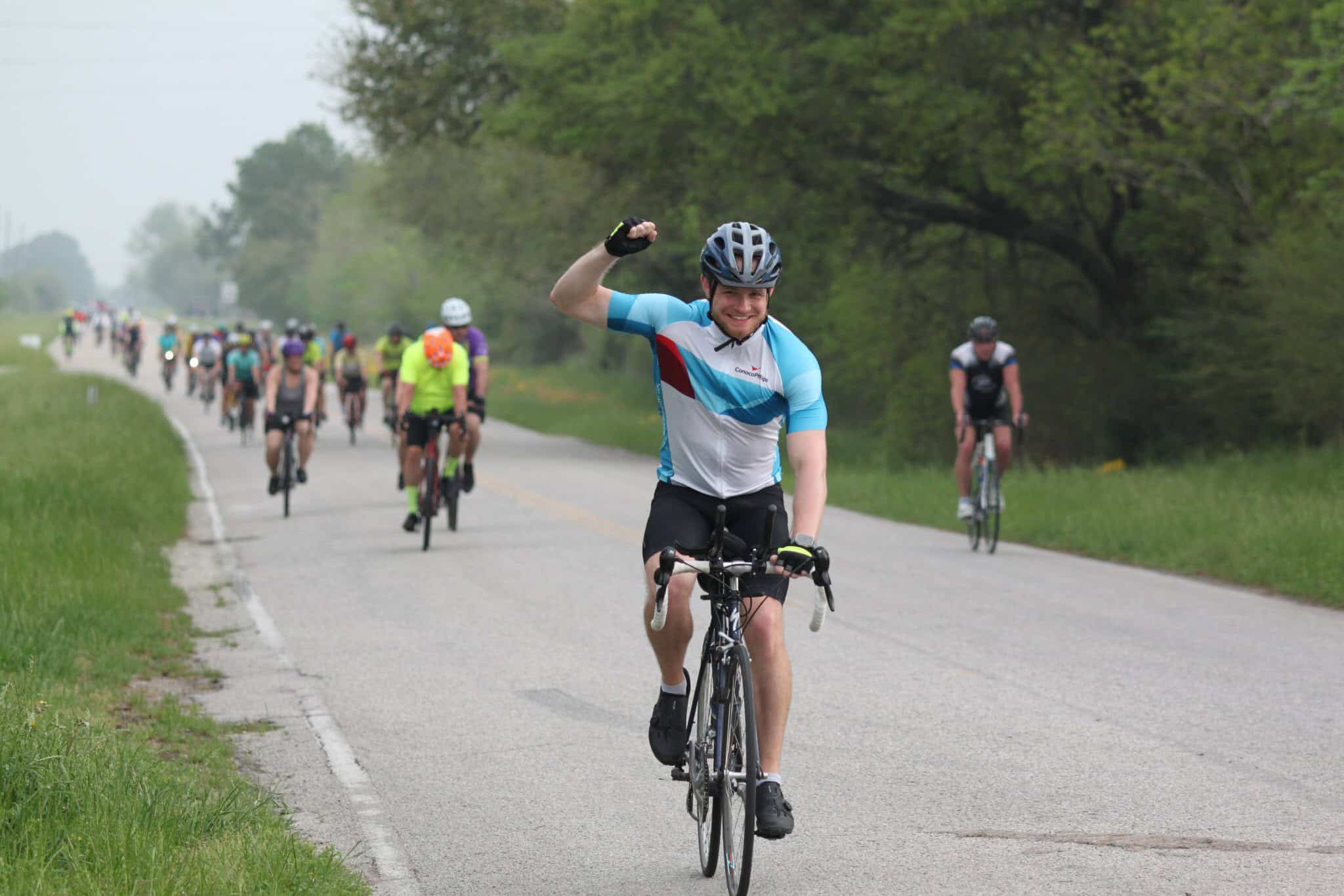 Bright cyclist celebrating during Bluebonnet Express bike event on scenic rural road.