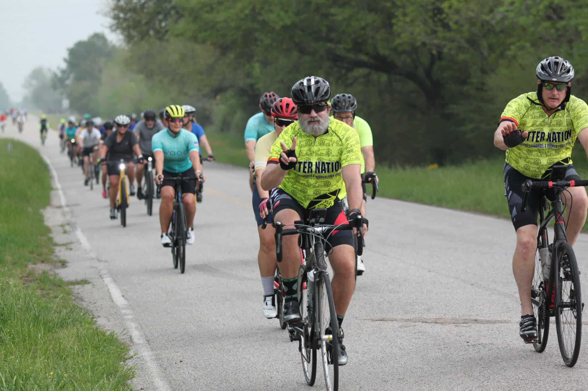 Vibrant group of cyclists riding along a rural road during Bluebonnet Express event.