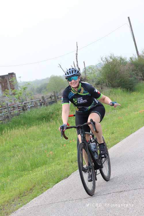 Bright female cyclist riding on scenic countryside road during Bluebonnet Express event.