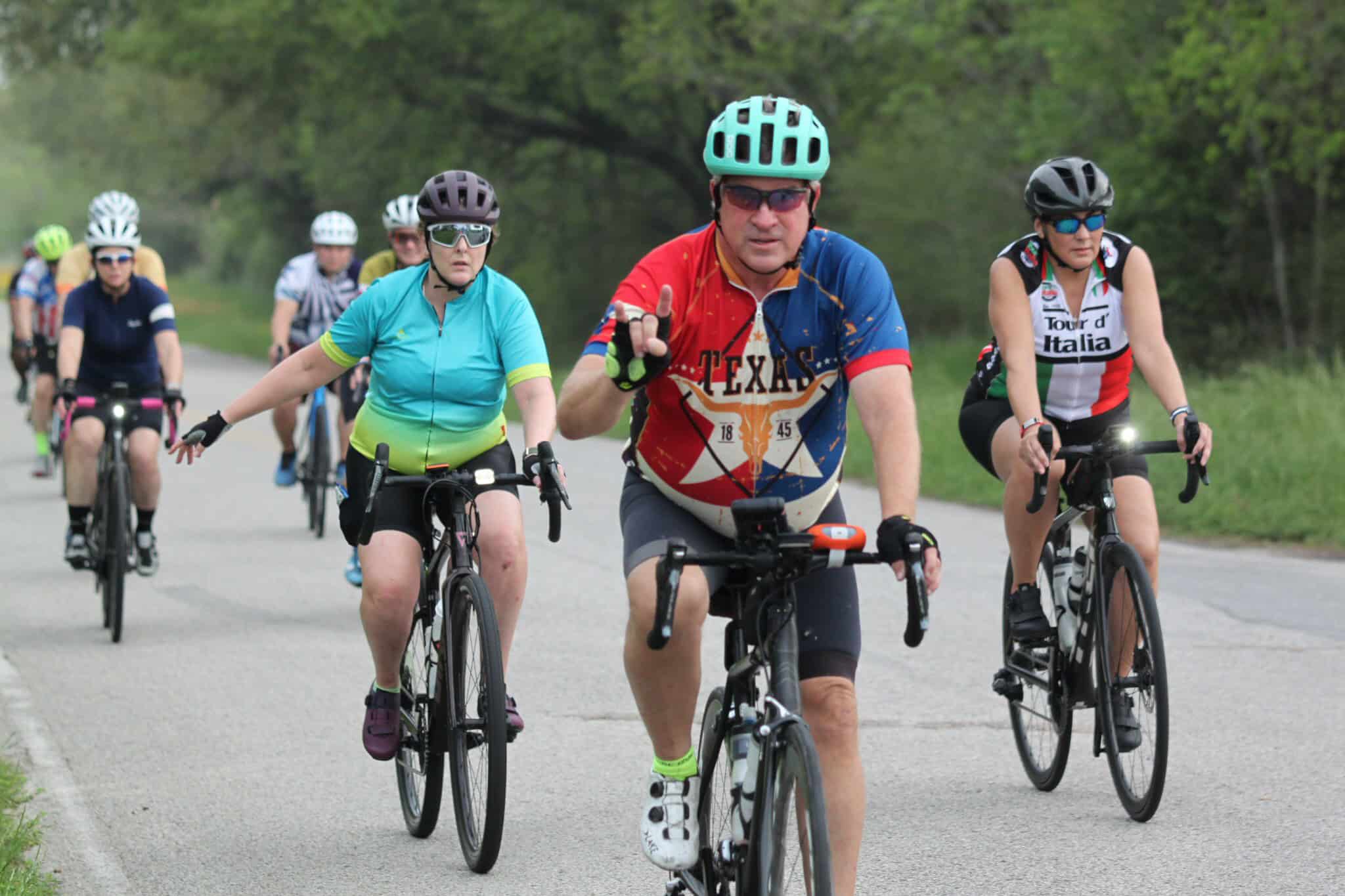 Bike ride with cyclists on scenic outdoor trail, Texas-themed cycling jersey, group cycling event, outdoor recreation, cycling adventure.