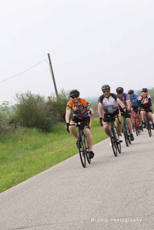 Vibrant group of cyclists riding on a scenic rural road for outdoor biking adventure.