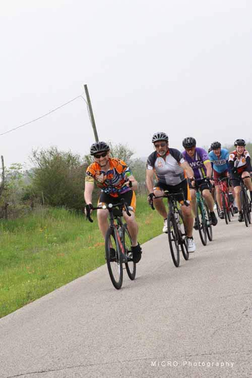 Vivid group of cyclists riding along a rural road during Bluebonnet Express event in Texas.