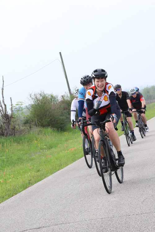Group of cyclists riding on a rural road, promoting Bluebonnet Express cycling events and scenic bike tours.