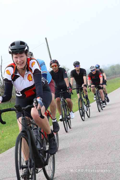 Bright smiling cyclist leading group during Bluebonnet Express ride, promoting fun outdoor cycling events and community health.