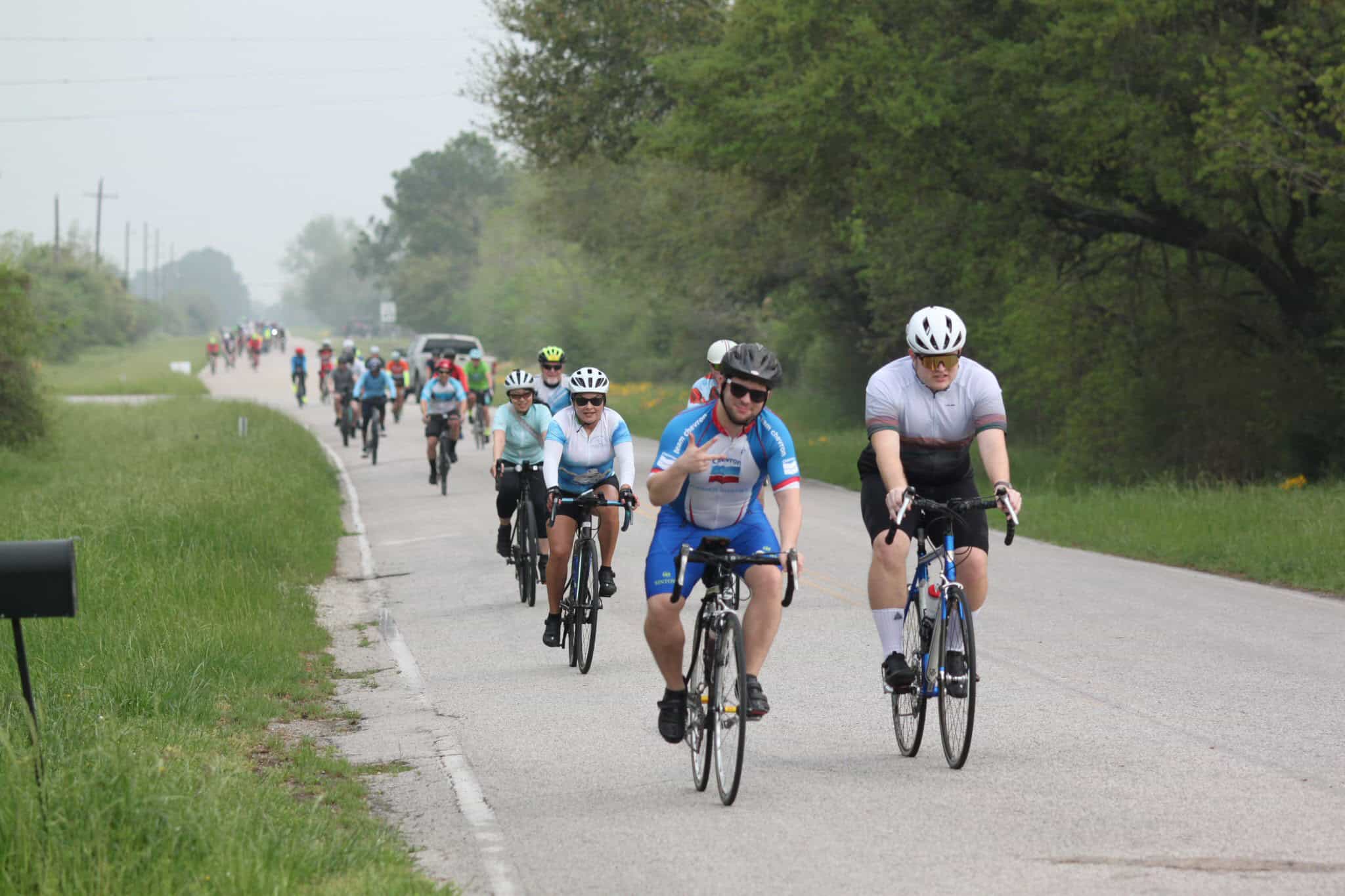 Bike riding event on rural road with group cyclists, emphasizing Bluebonnet Express cycle tour.