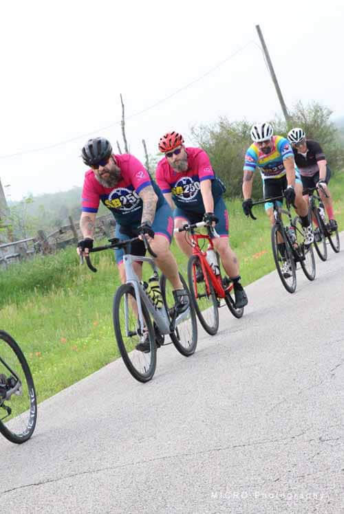 High-performance cyclists riding on scenic rural road during Bluebonnet Express event.
