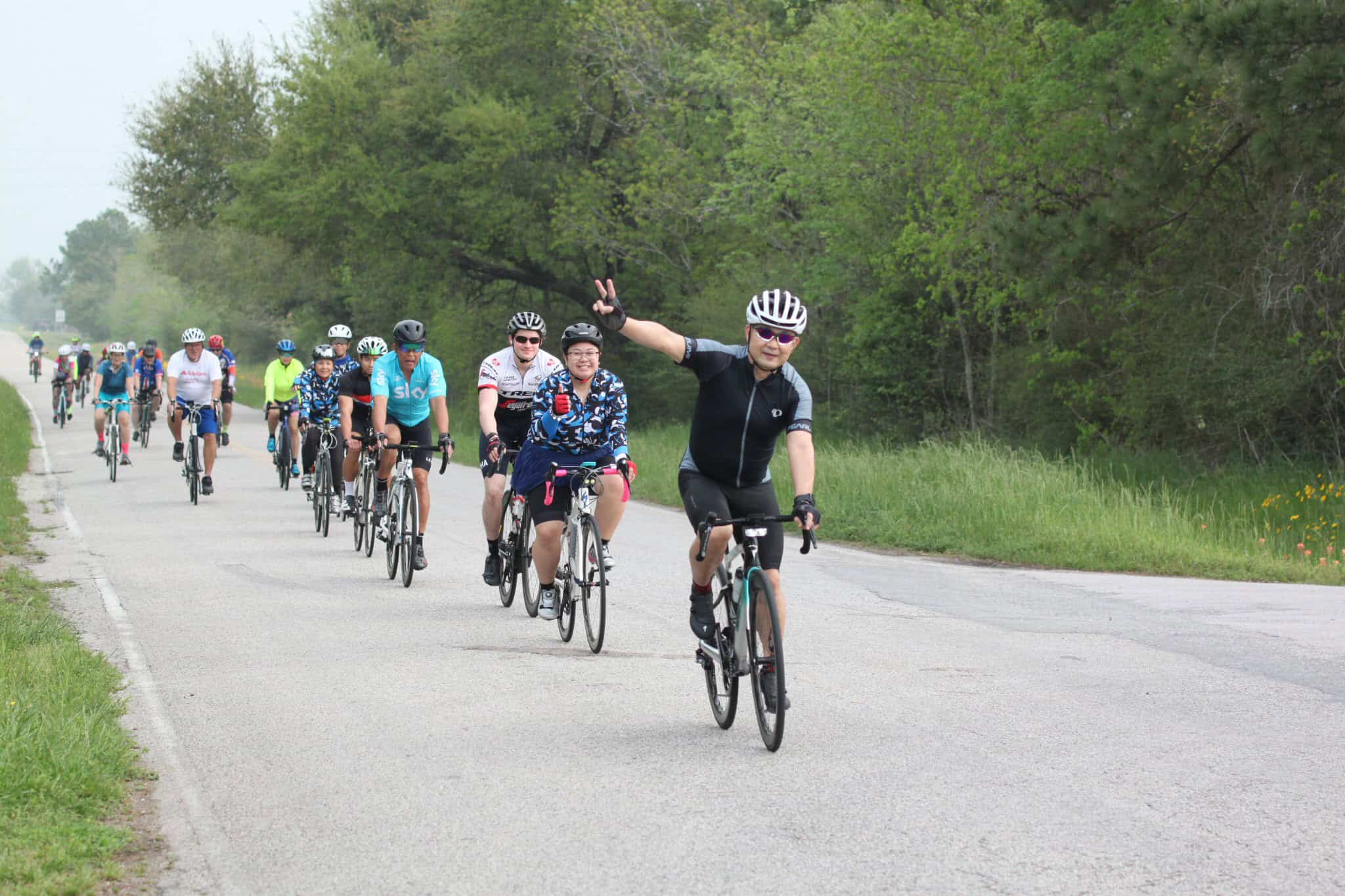 Vibrant group of cyclists participating in Bluebonnet Express charity ride on scenic rural route.
