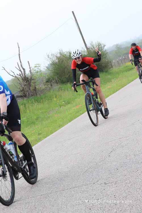 Bright smiling cyclist waving on scenic Bluebonnet Express bike trail during daytime.