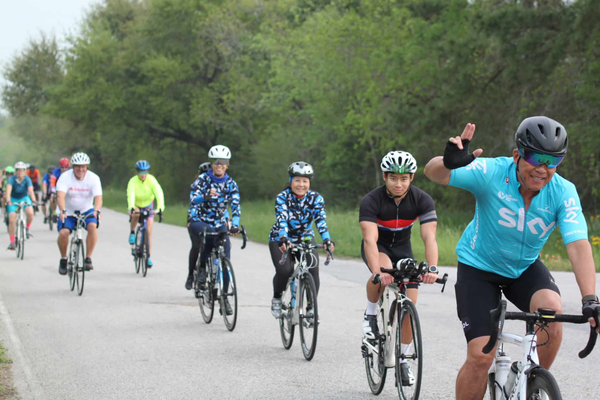 Vibrant group of cyclists riding on a scenic trail with lush greenery in the background.