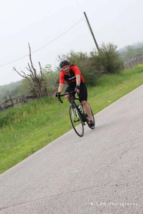 Bright cyclist riding on rural road during daytime - Bluebonnet Express biking adventure.