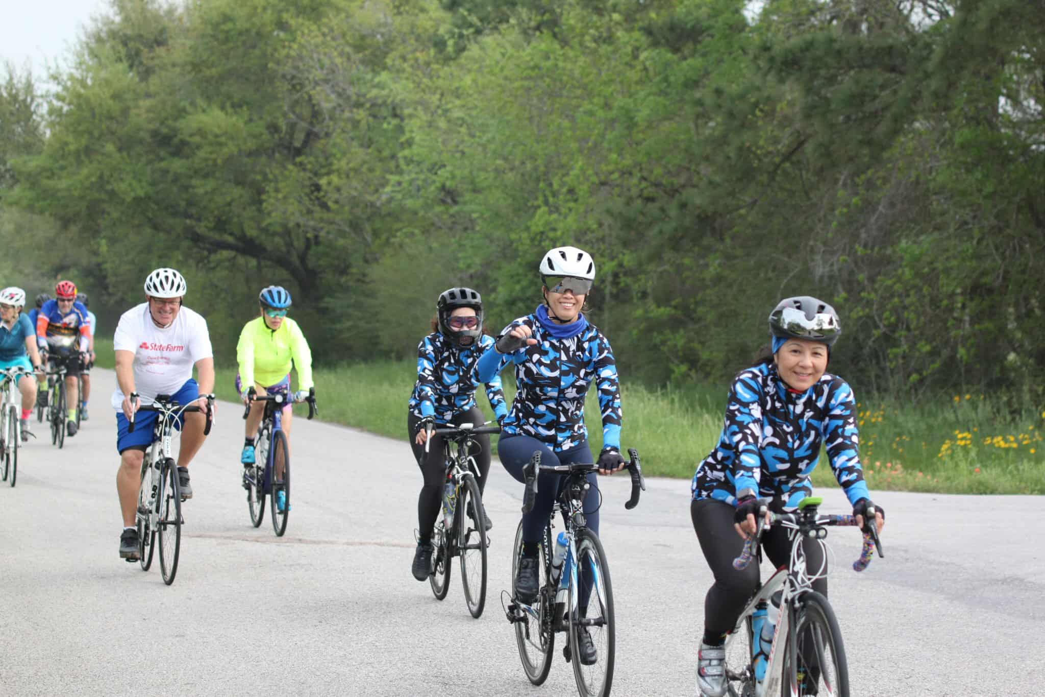 Vibrant group cycling on scenic trail with lush greenery during Bluebonnet Express event.