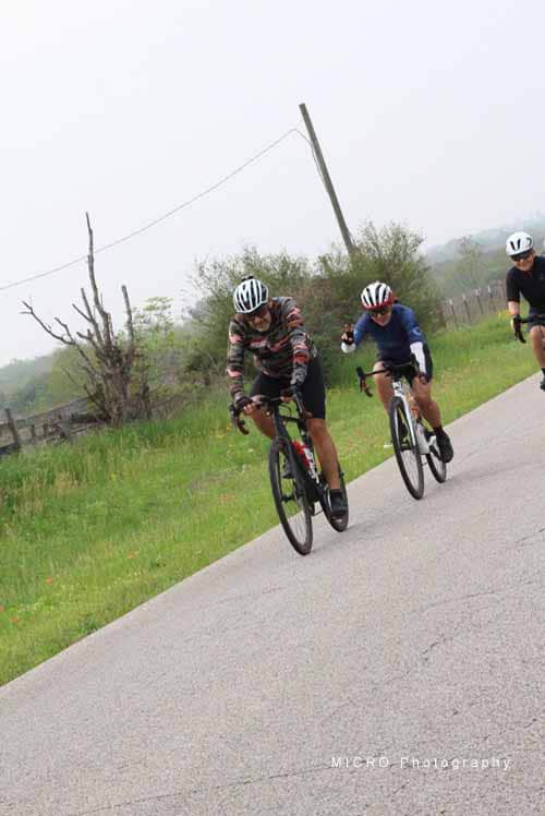 Vibrant cyclists riding on a scenic rural road during the Bluebonnet Express event.