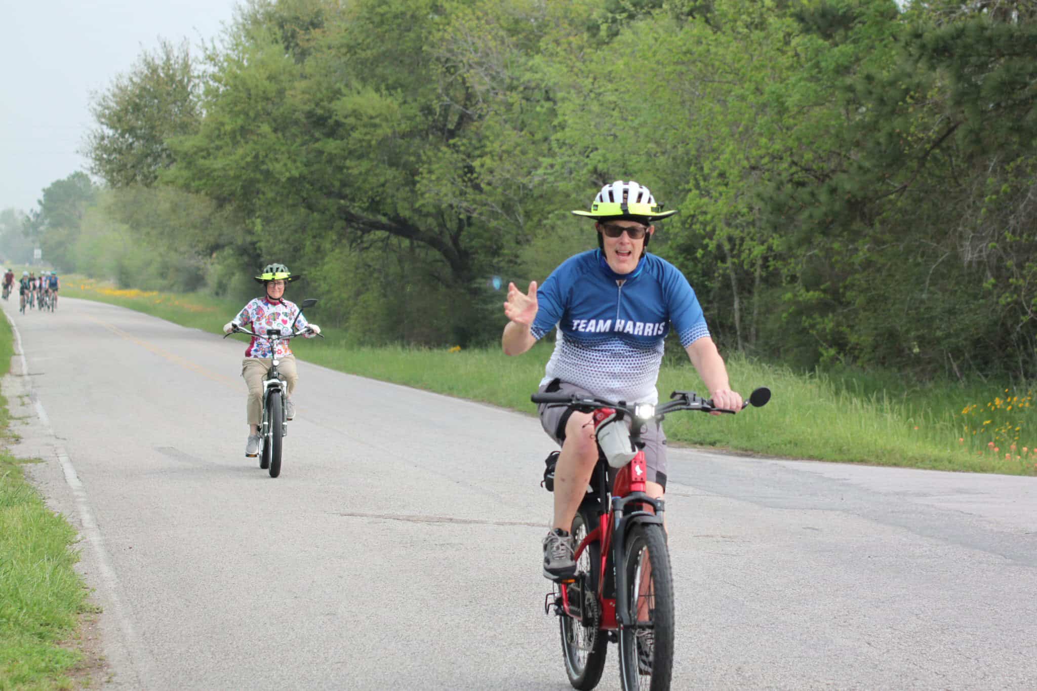 Bright cyclist with "Team Harris" jersey riding on scenic bike trail during Bluebonnet Express event.