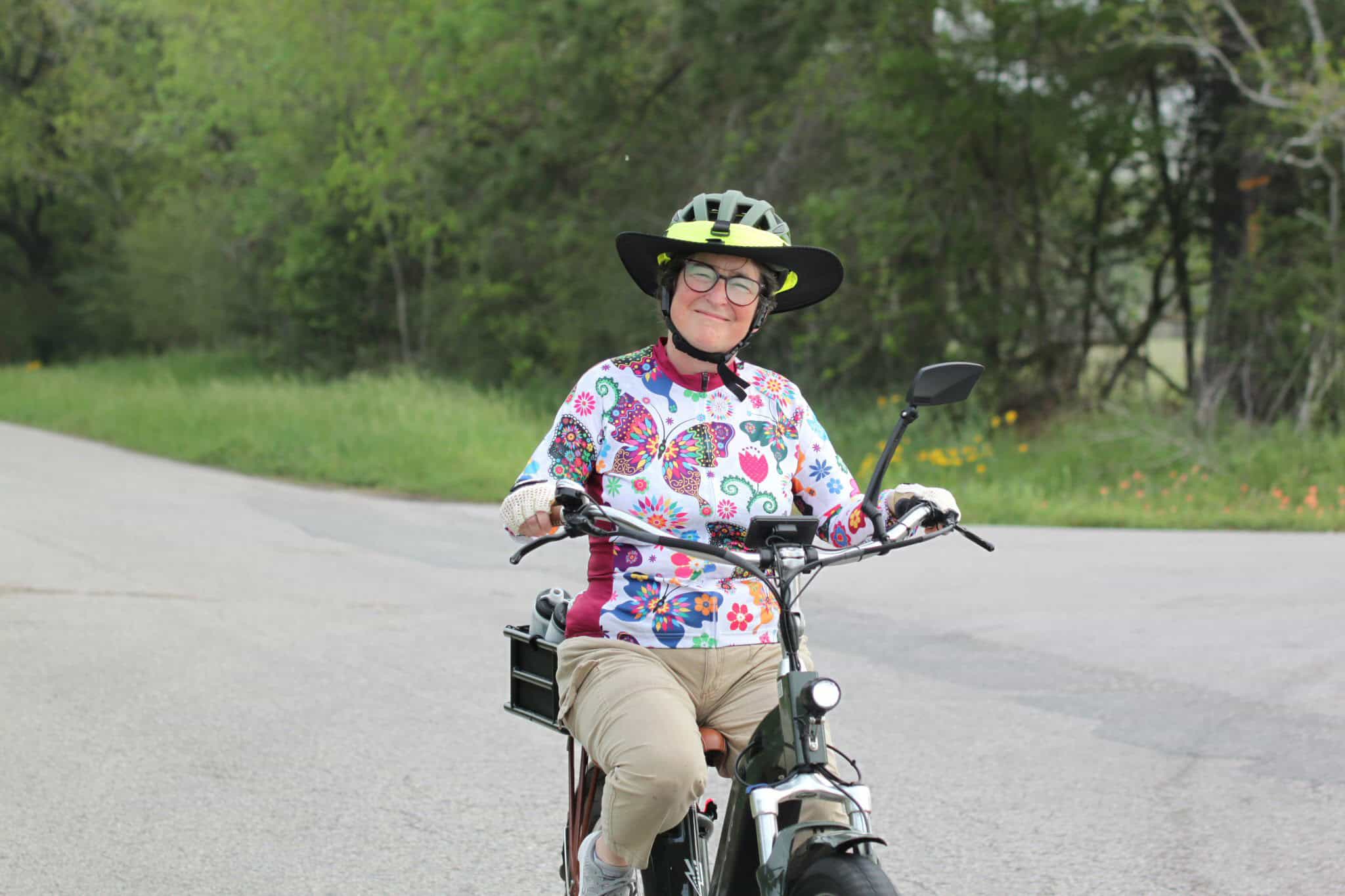 Vibrant woman riding an electric bike on a scenic outdoor trail with lush greenery.