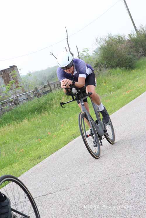Bright cyclist wearing a helmet riding an e-bike on a scenic trail in Texas.