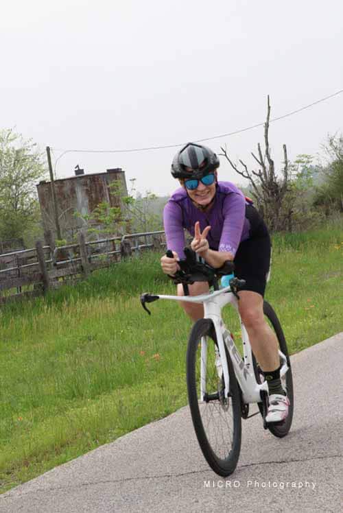 Bright woman cycling on a road in outdoor setting, promoting Bluebonnet Express bike services.