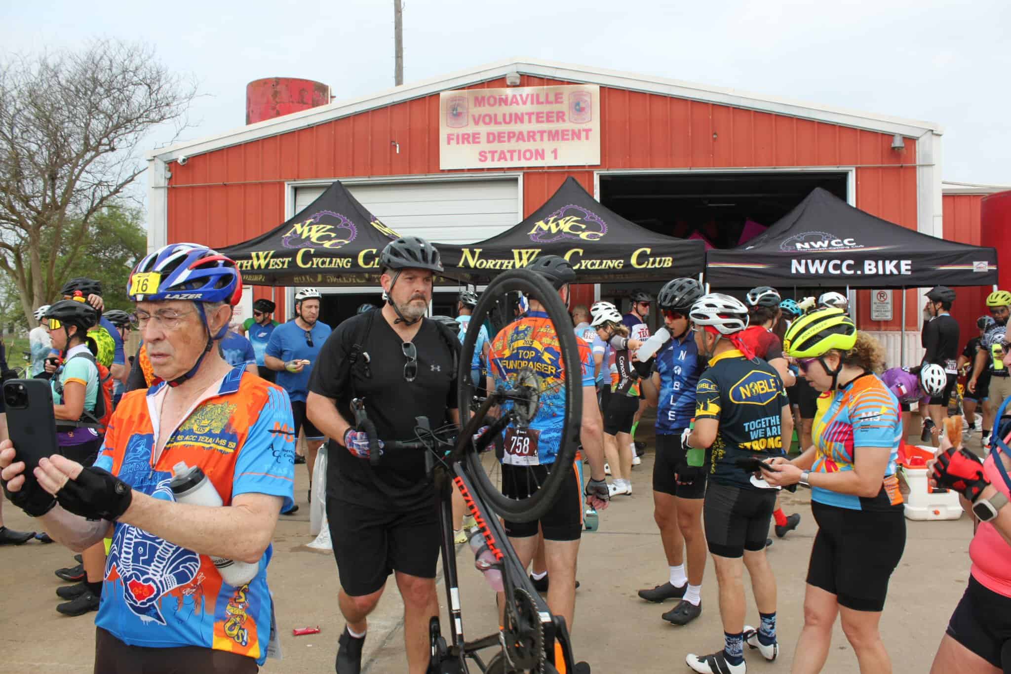 Cycling event at Monaville Volunteer Fire Station with NWCC Bike tents, featuring cyclists and supporters.