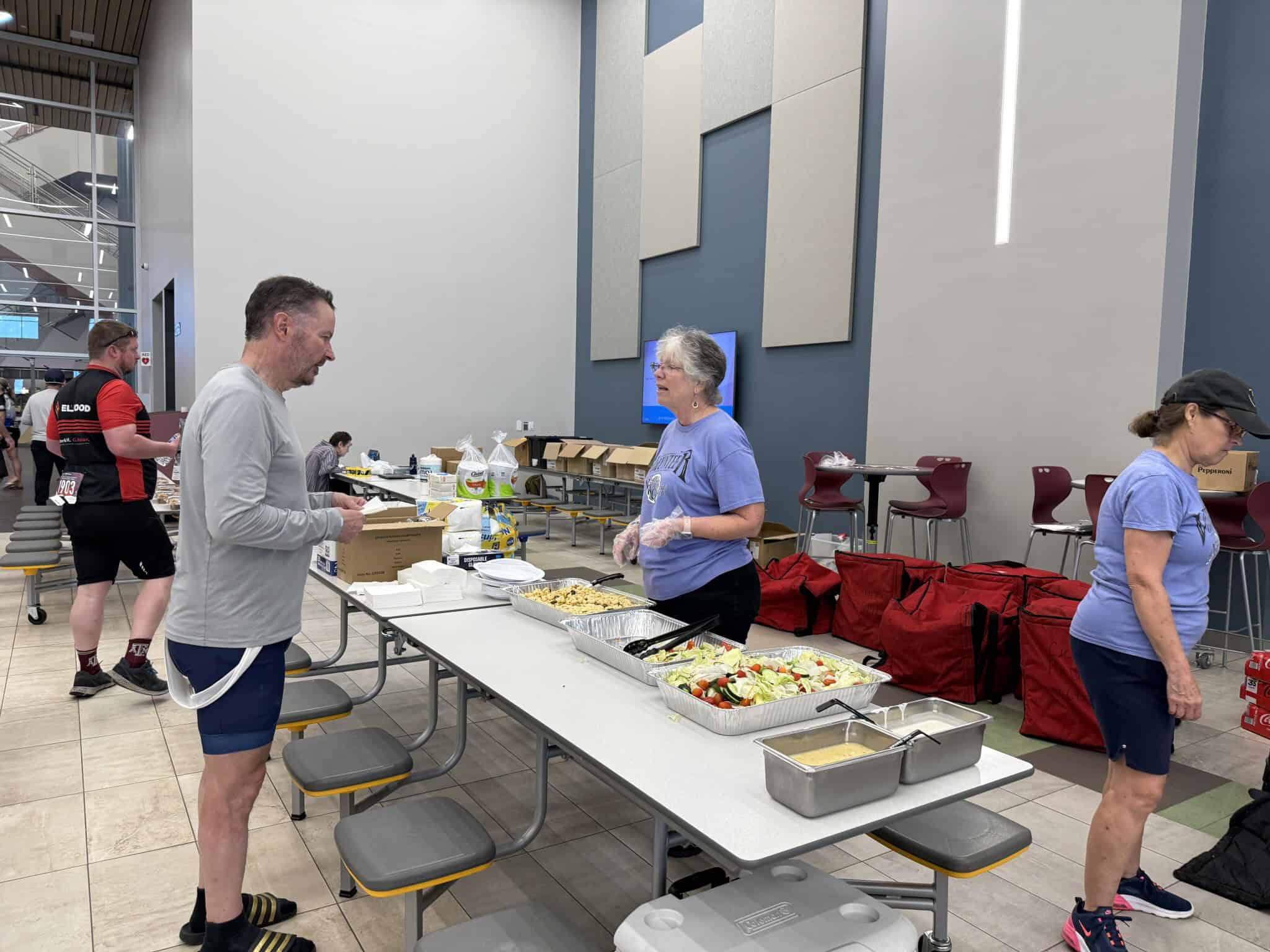 Bright indoor event with volunteers serving food at a community gathering.