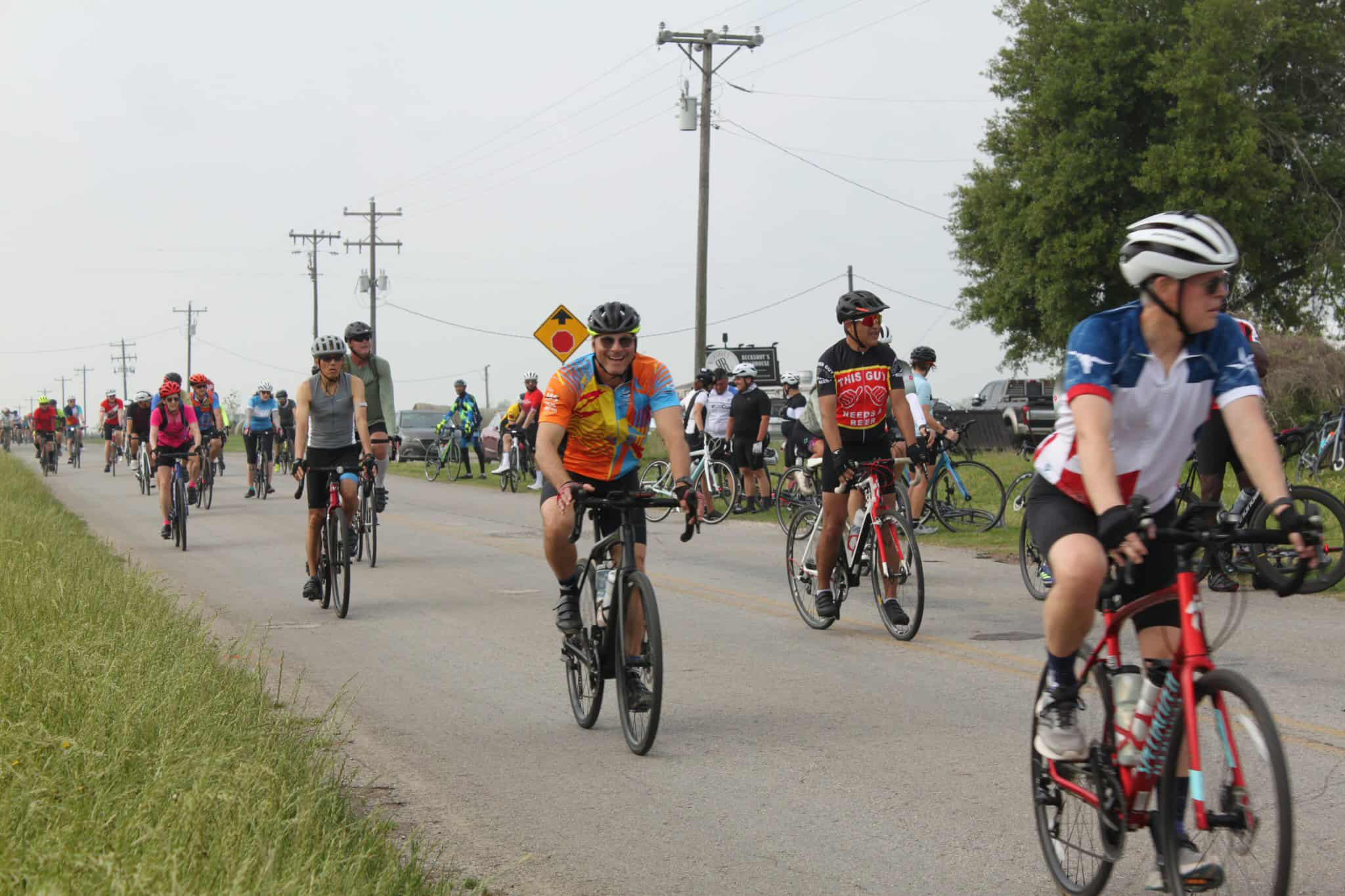 Vibrant group of cyclists participating in Bluebonnet Express charity bike ride on a rural country road.