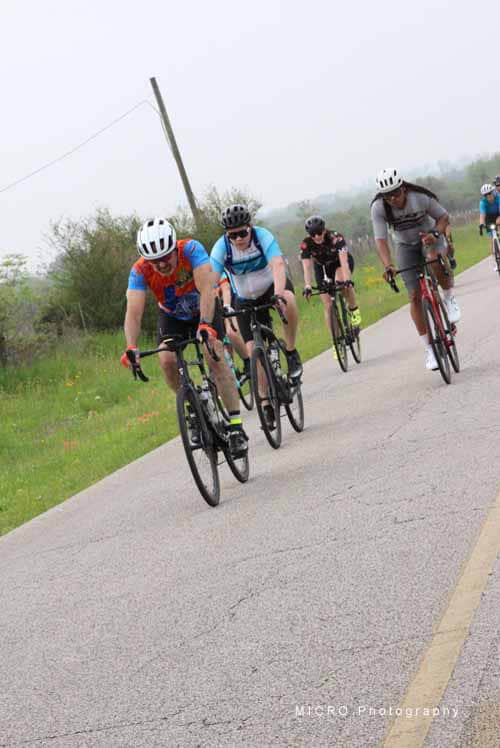 Group of cyclists riding on a rural road during daytime, enjoying a bicycle ride.