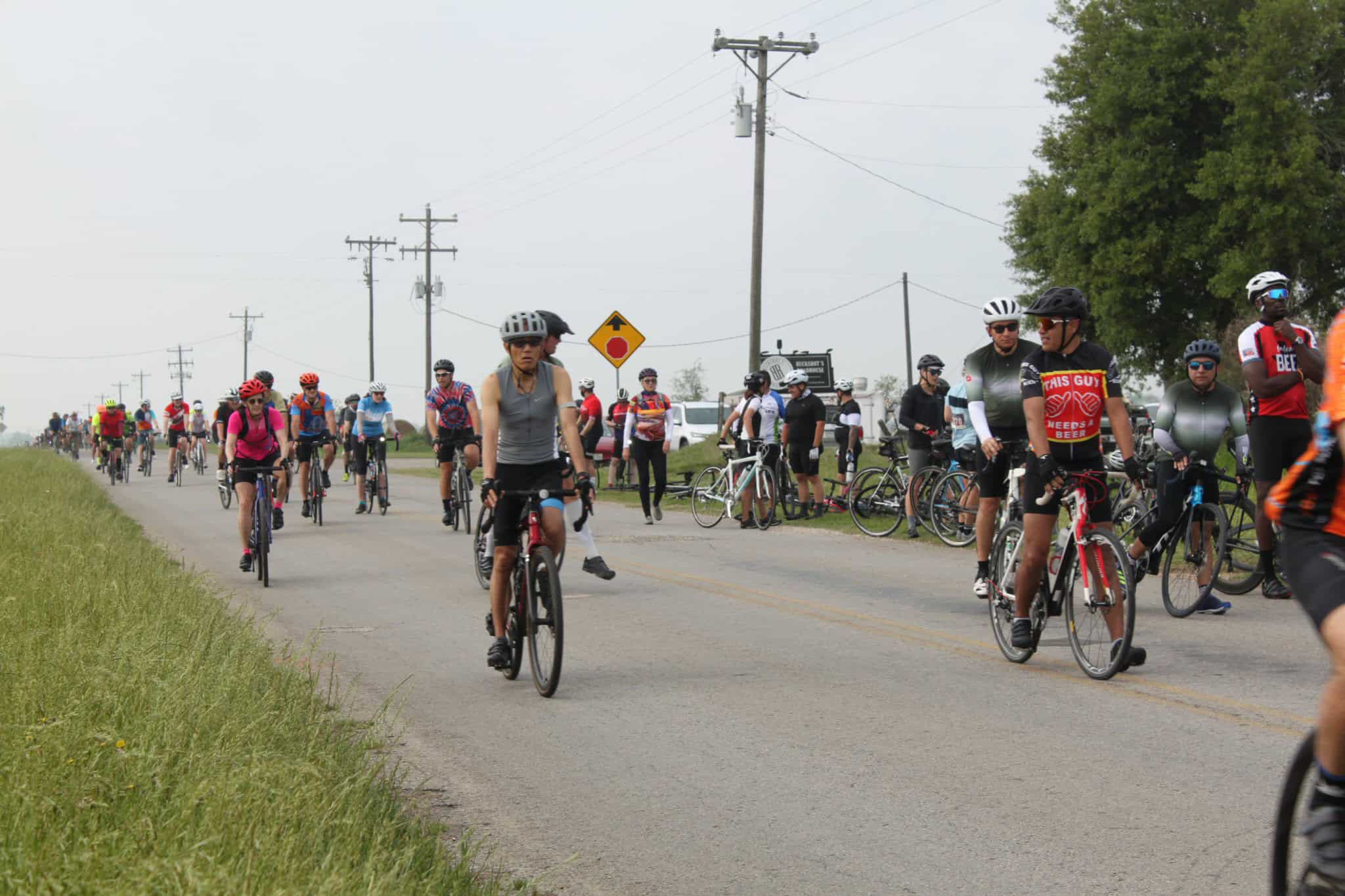 Vibrant group cycling event on Bluebonnet Express route with diverse riders and scenic rural backdrop.