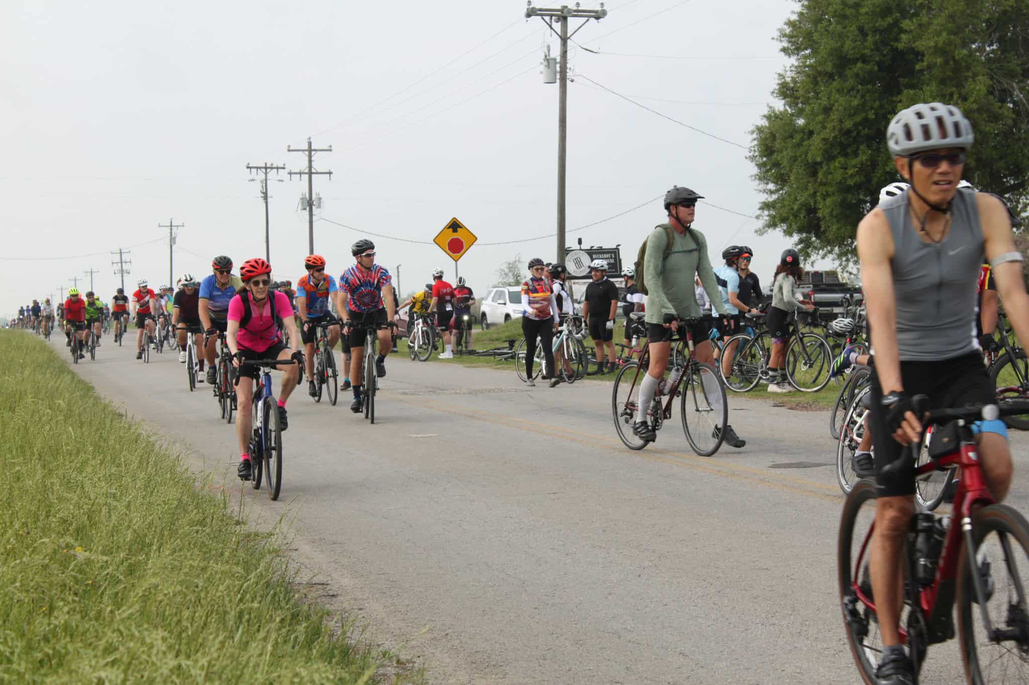 Spectators and cyclists at Bluebonnet Express bike race event in Texas countryside.