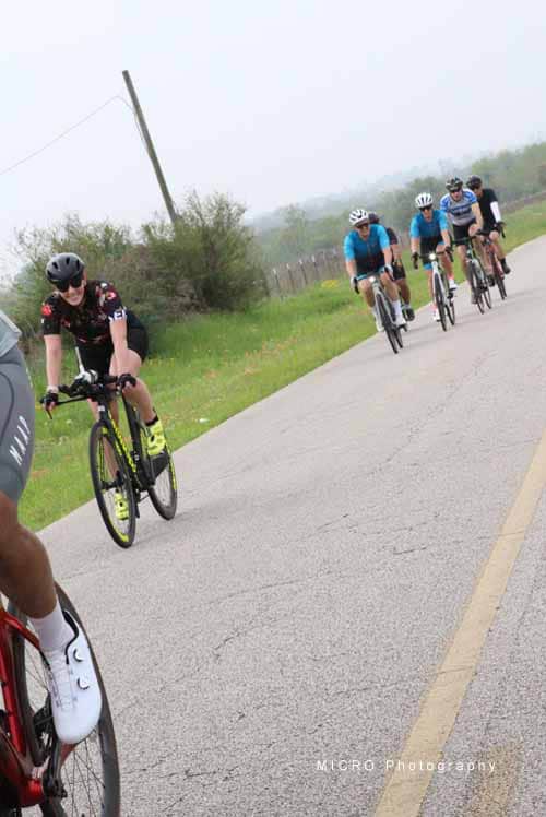 Bright group of cyclists enjoying Bluebonnet Express scenic bike ride along rural Texas roadside.