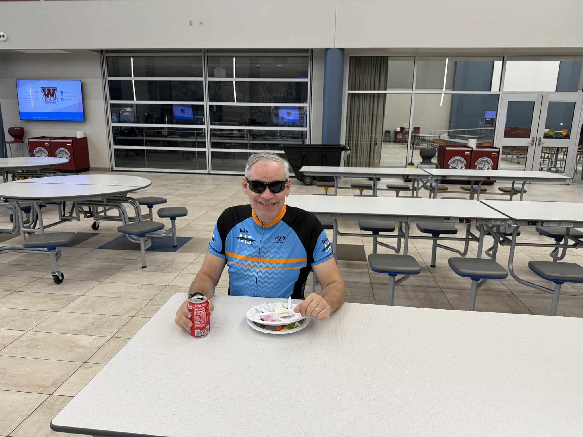 Refreshing cyclist at Bluebonnet Express, enjoying snacks in a modern, spacious dining area. Perfect break during bike trip.