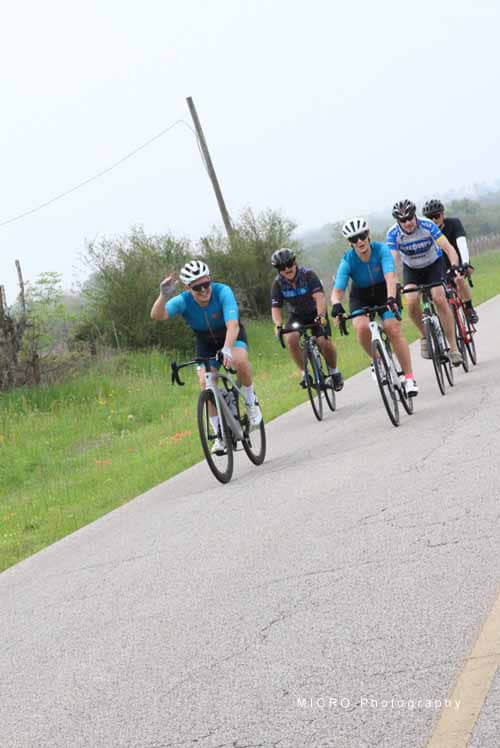 Vibrant cyclists enjoying Bluebonnet Express scenic ride on a rural Texas road.