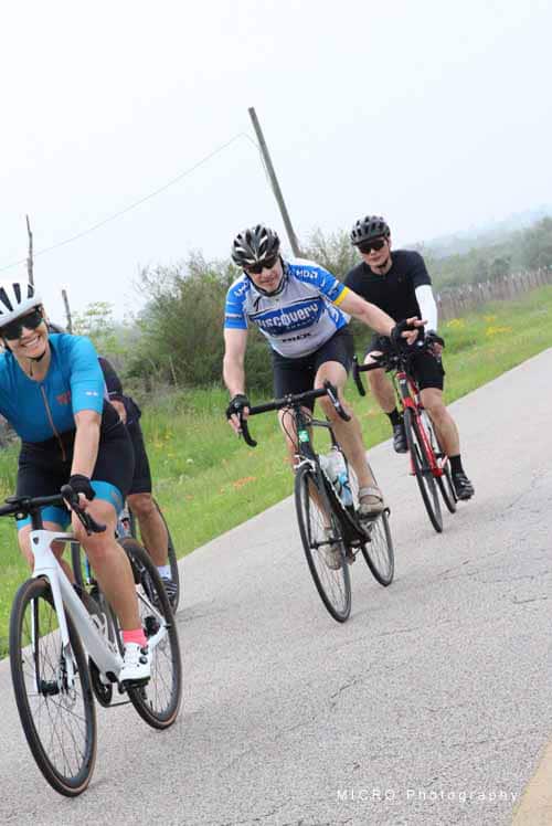 Cyclists riding on a scenic rural road during Bluebonnet Express event.