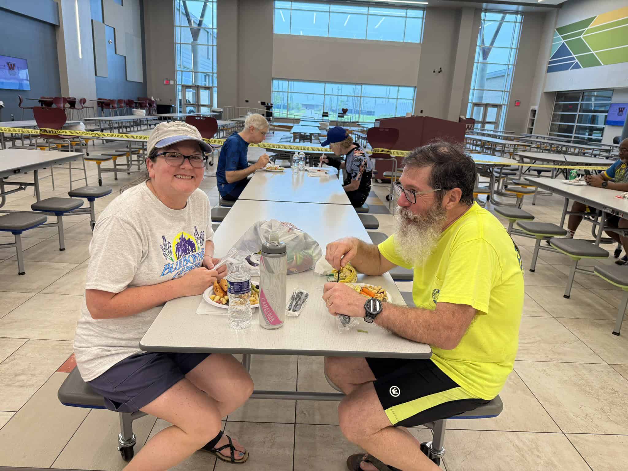 Smiling cyclists enjoying a meal at a cafeteria during Bluebonnet Express event.